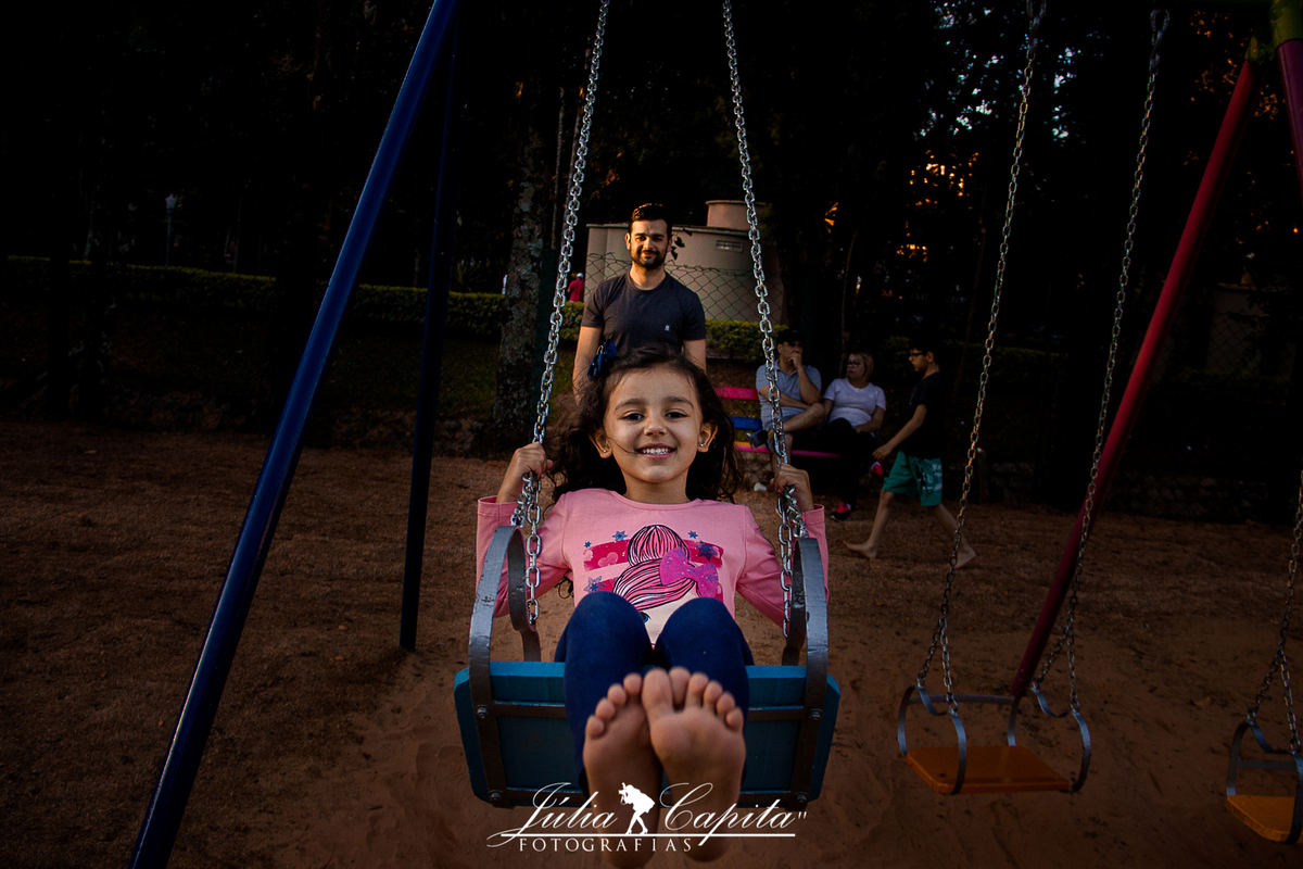 Pai brincando com a filha no balanço em ensaio fotográfico por Júlia Capita
