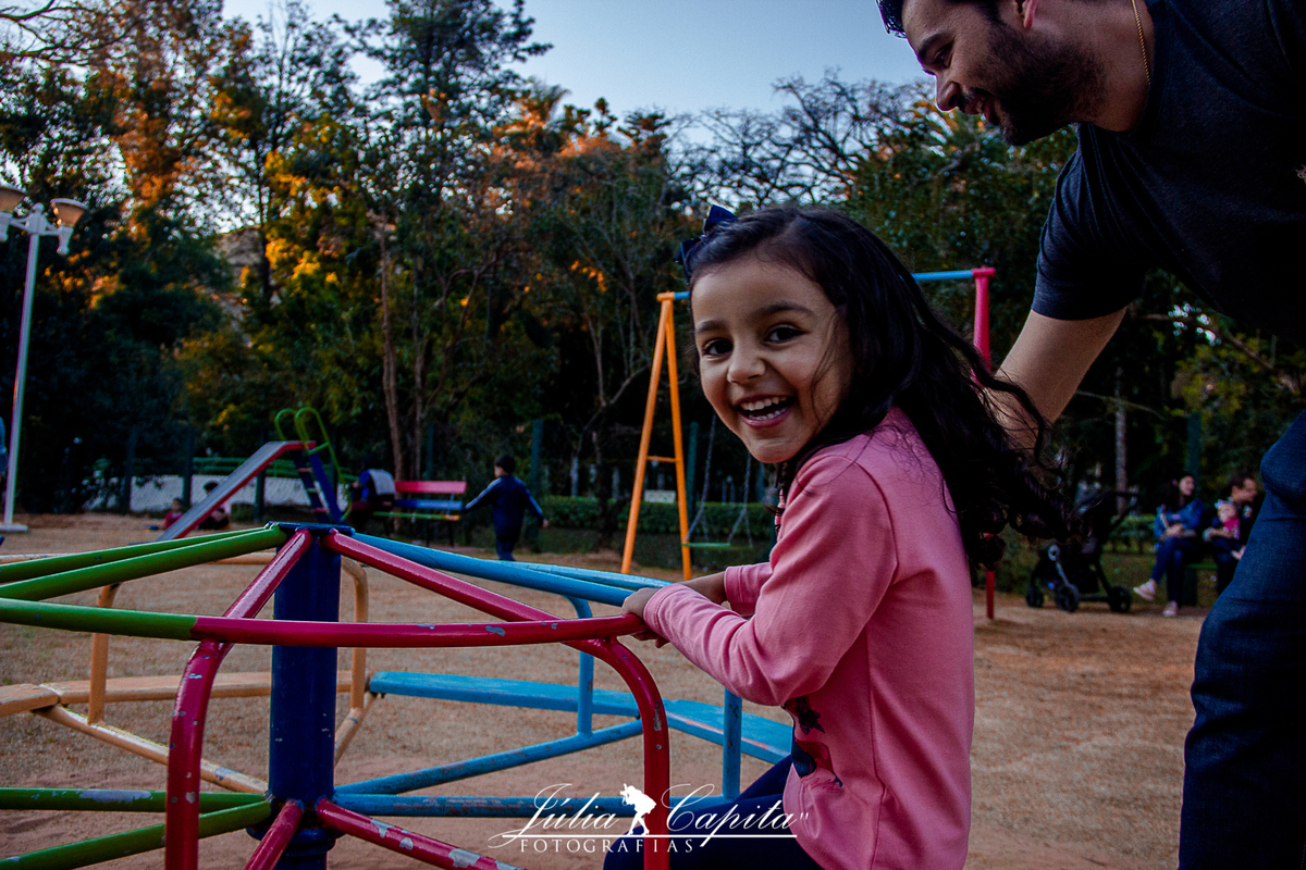 Filha brincando com o pai em ensaio fotográfico infanil