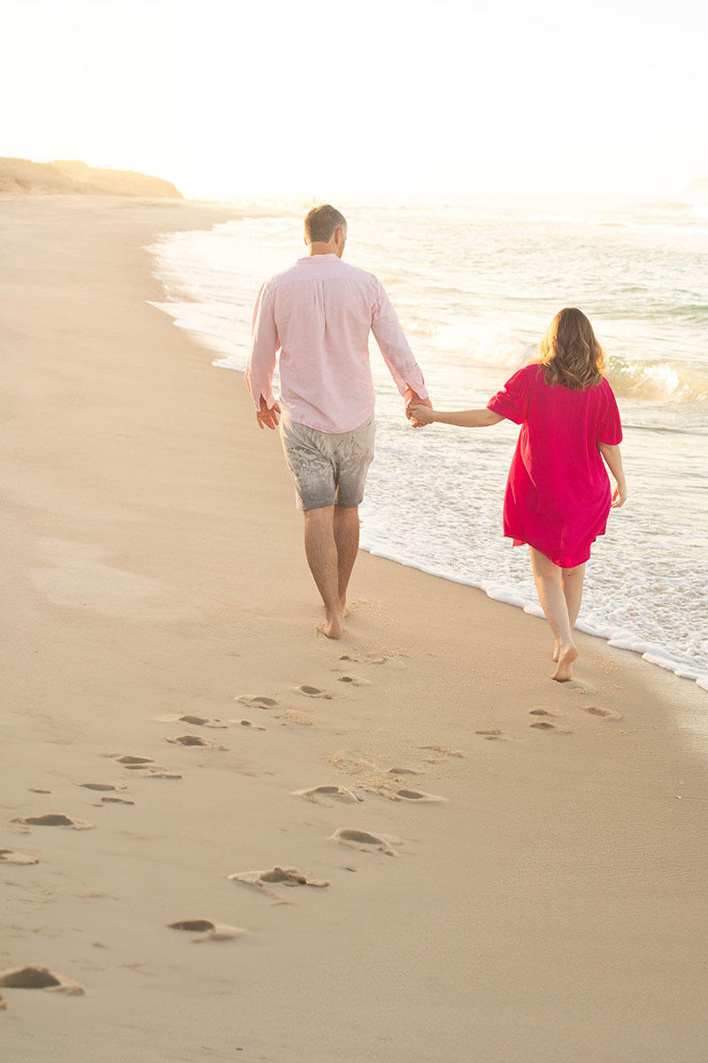 Casal caminhando à beira-mar durante ensaio gestante na Praia da Barra