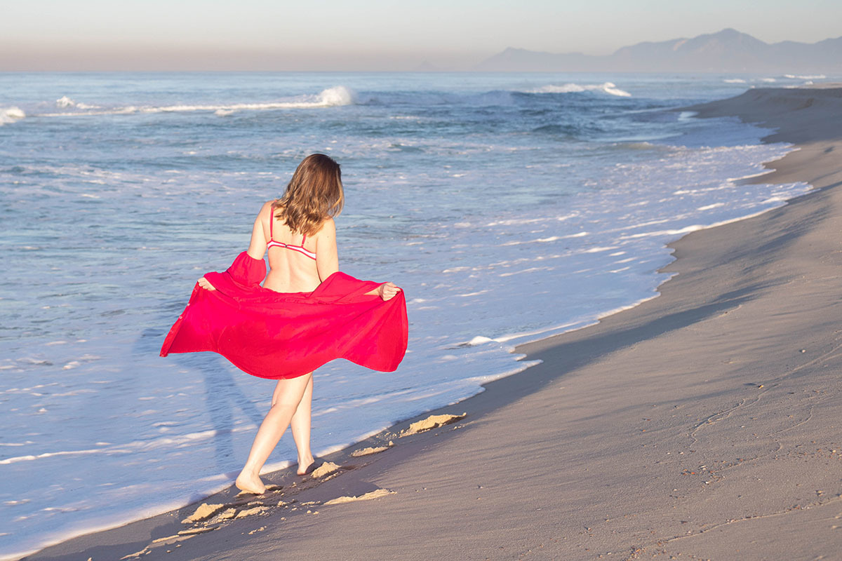 Mãe grávida caminhando sozinha à beira-mar na Praia da Barra