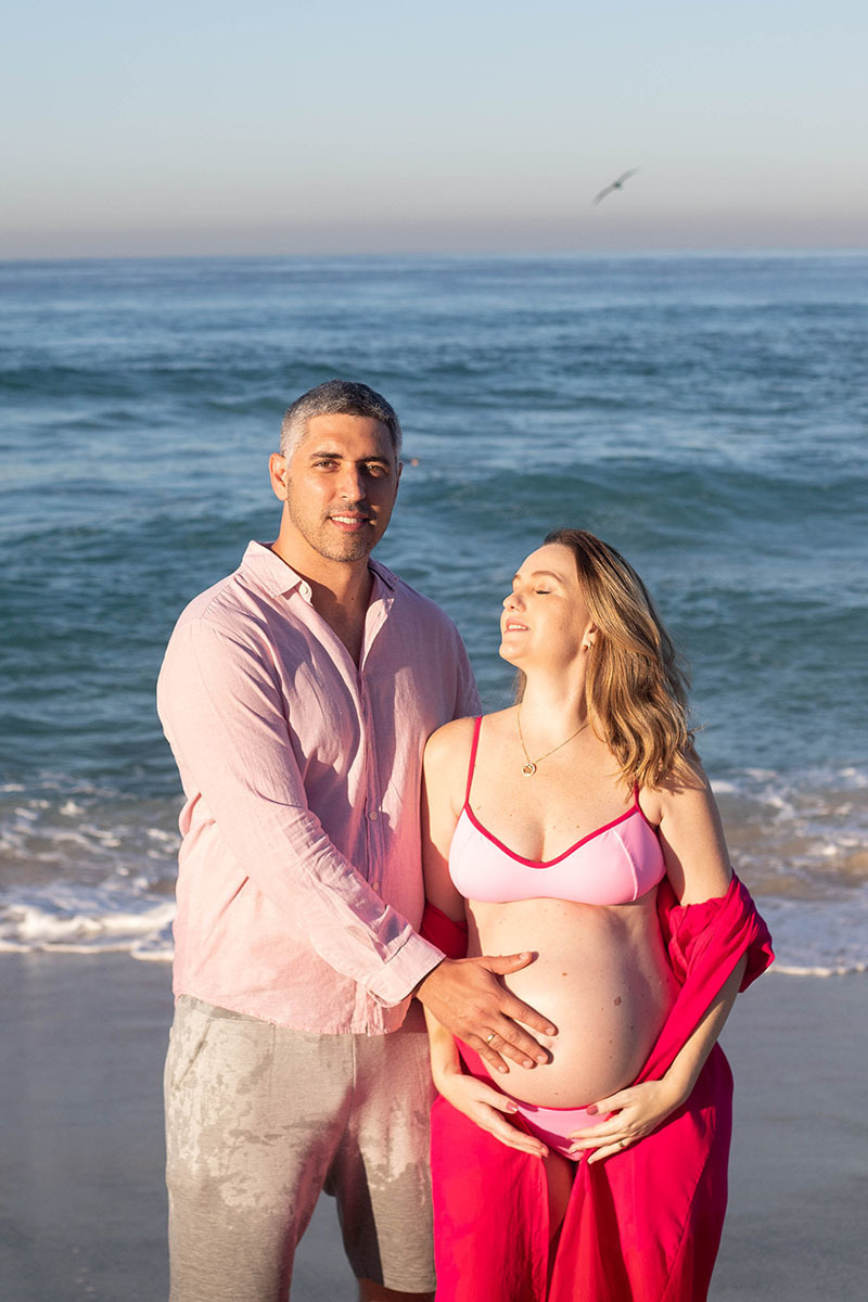 Casal à espera do bebê em cenário de luz dourada na Praia da Barra