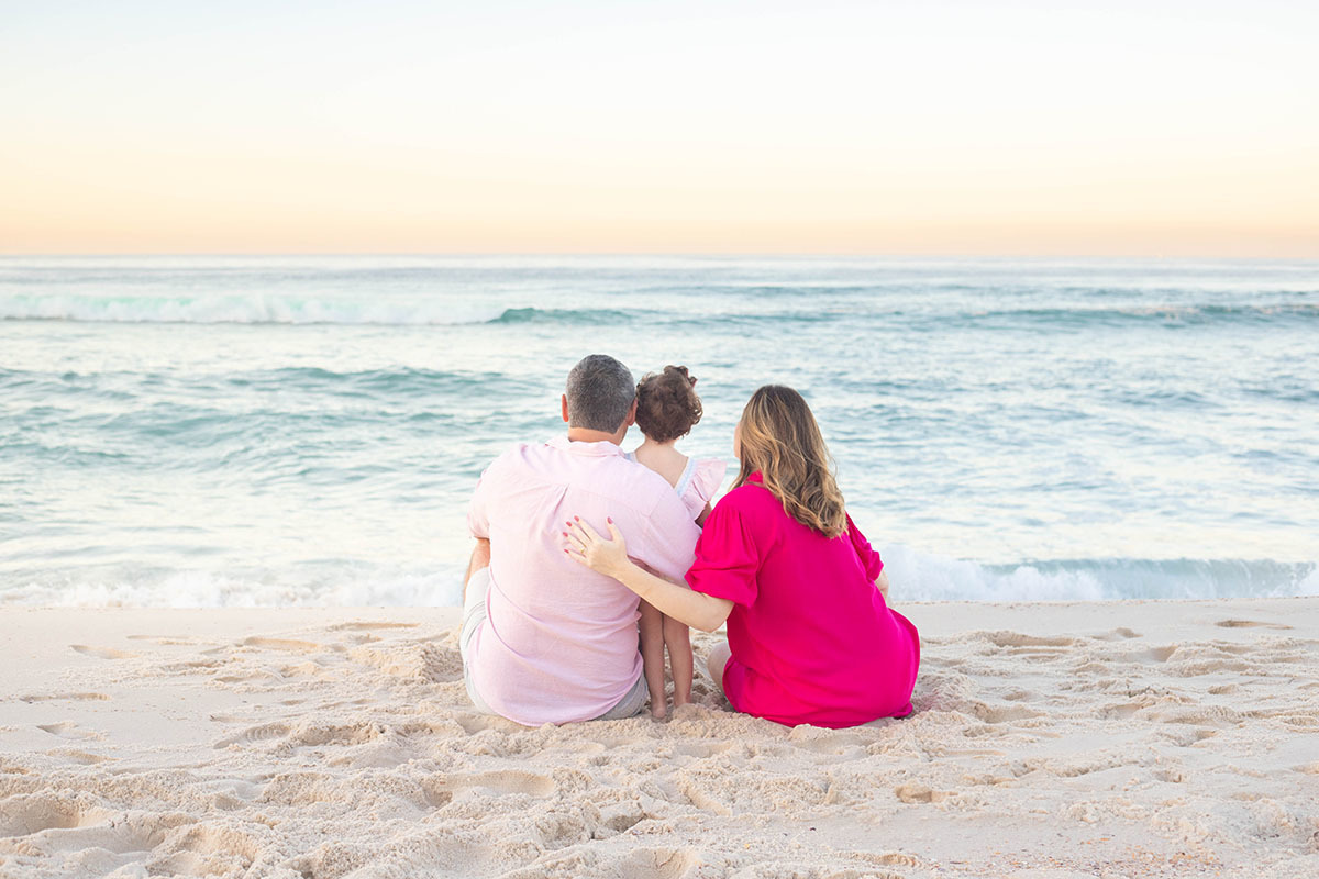 Momento de conexão entre mãe, pai  e filha em ensaio gestante na praia