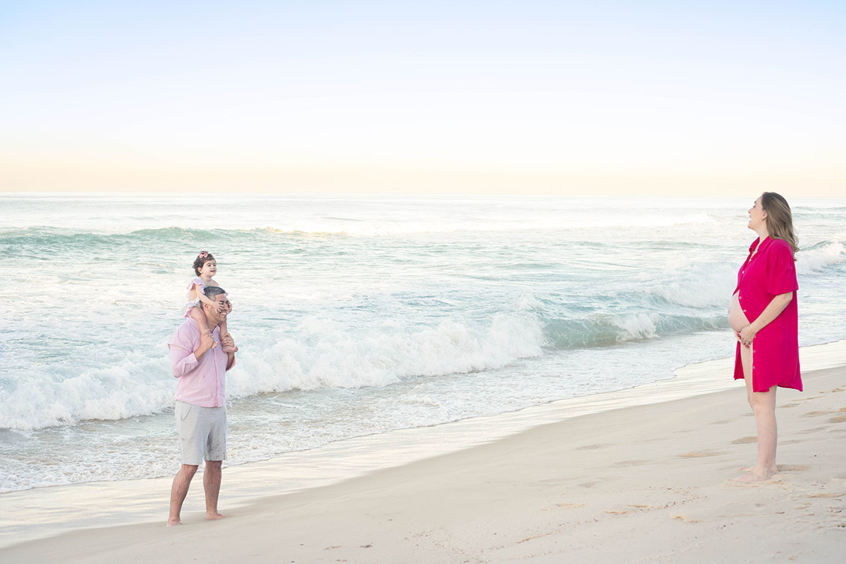 Família sorrindo e curtindo o mar em ensaio gestante na Barra