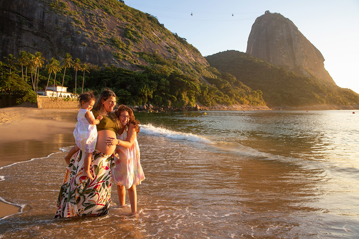 gestante com filhas na Praia Vermelha com o Pão de Açúcar ao fundo - ensaio gestante - Rio de Janeiro - RJ.