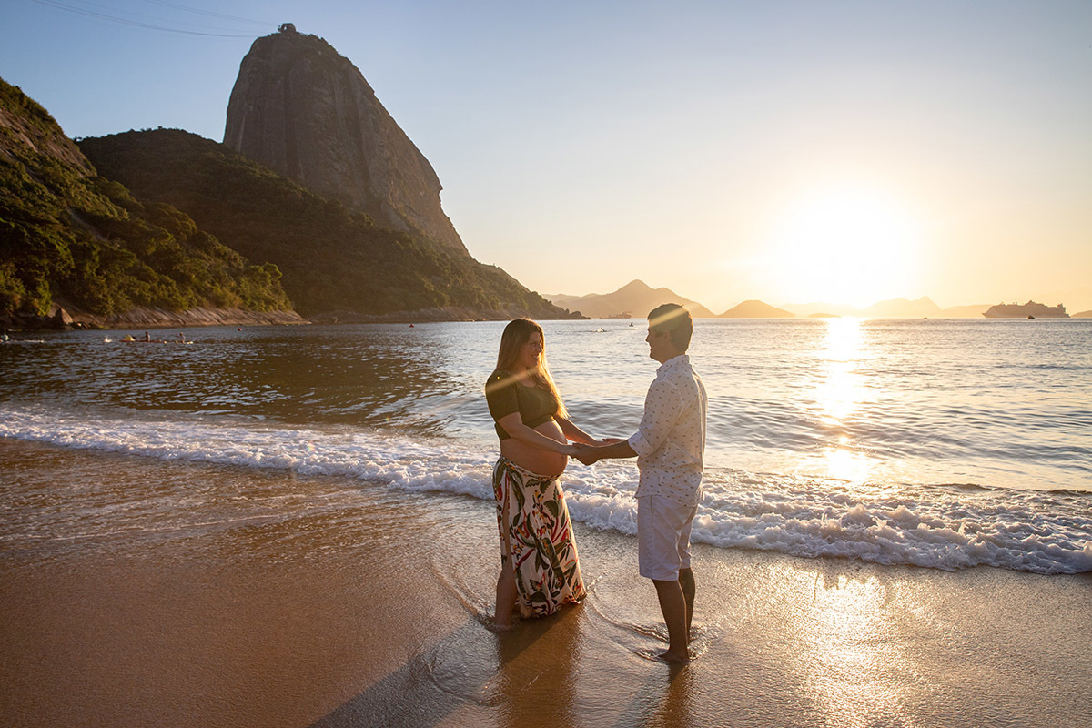 gestante e marido de mãos dadas na beira do mar da Praia Vermelha- ensaio gestante - Urca - Rio de Janeiro - RJ.