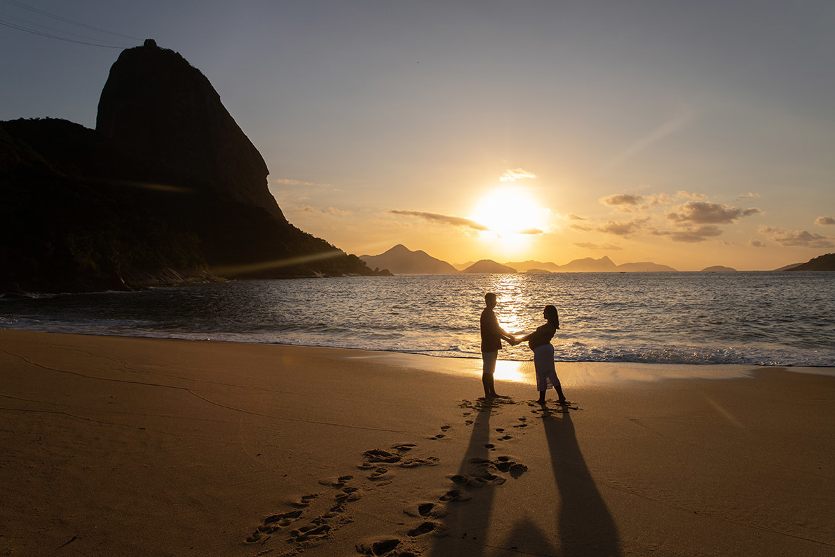 Silhueta de casal em ensaio de gestante com o Pão de Açúcar ao fundo.