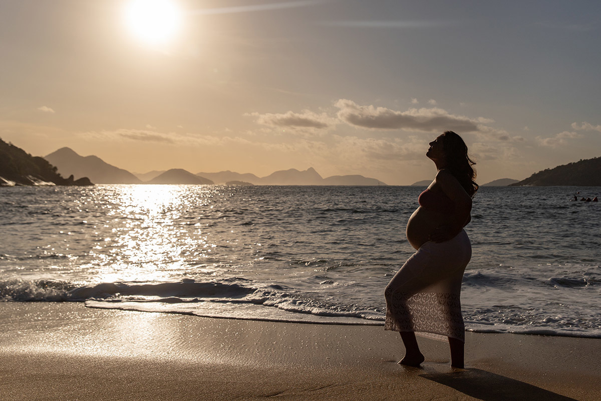 Silhueta de gestante com o mar ao fundo durante o ensaio na Praia Vermelha.