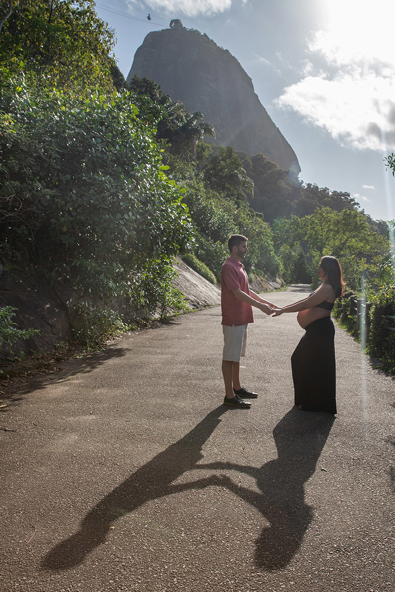Fotografia de gestante na Praia Vermelha com vegetação e montanhas ao fundo.