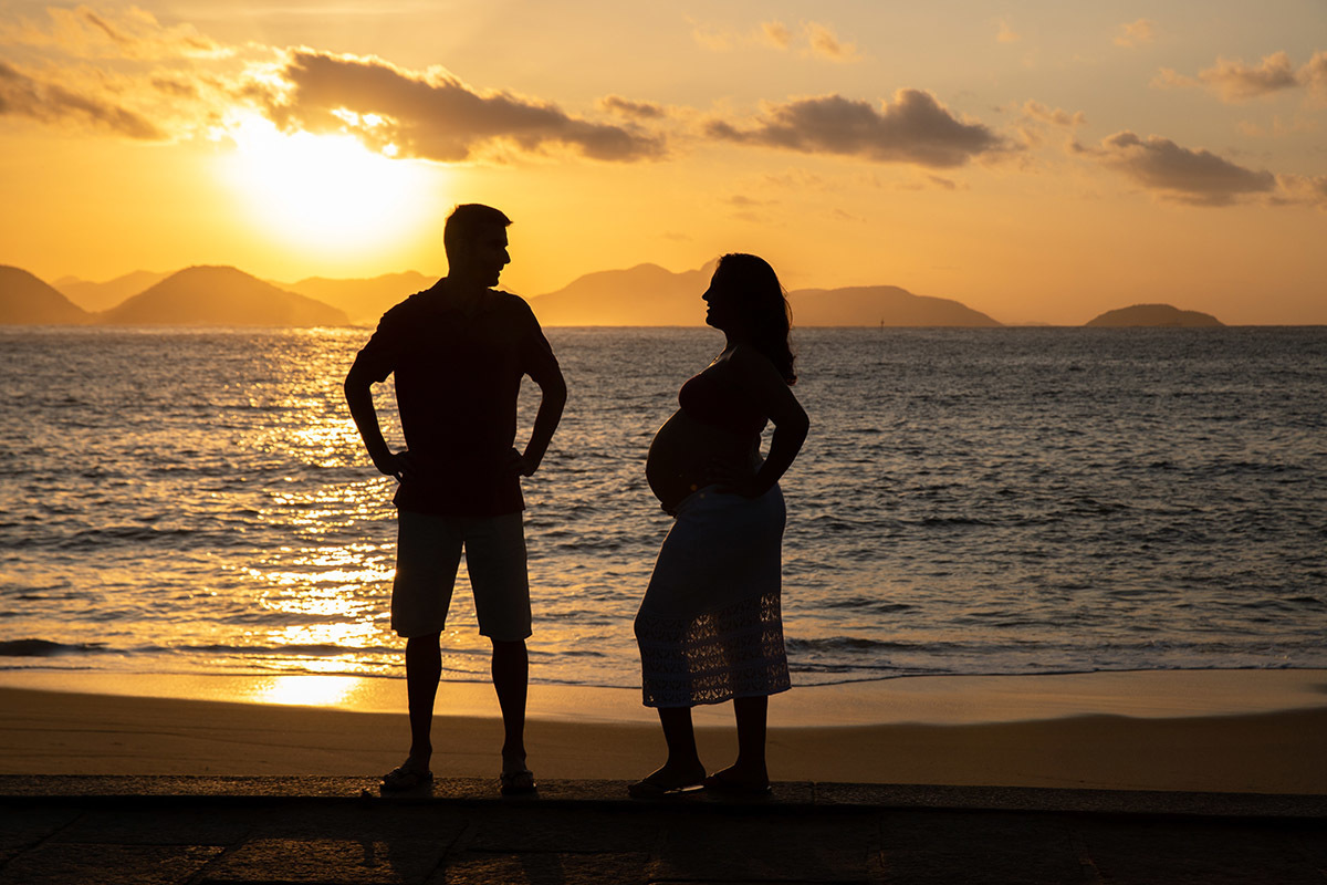 Silhueta de Casal trocando olhares em ensaio gestante na praia no Rio de Janeiro.