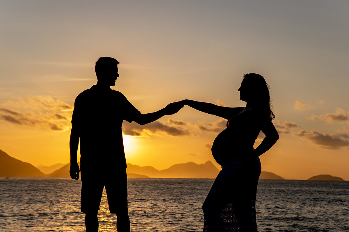 Silhueta de casal em ensaio gestante no nascer do sol na Praia Vermelha.