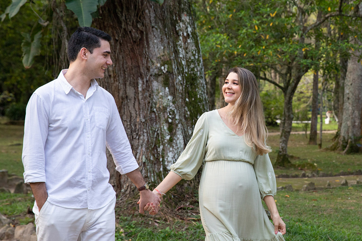 Casal caminhando em ensaio de gestante ao ar livre no Jardim Botânico do Rio.