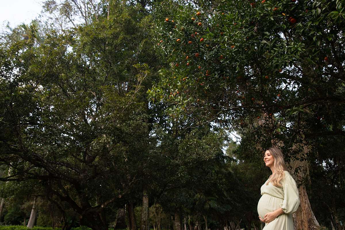 Foto de gestante sozinha no Jardim Botânico do Rio, destacando a barriga.