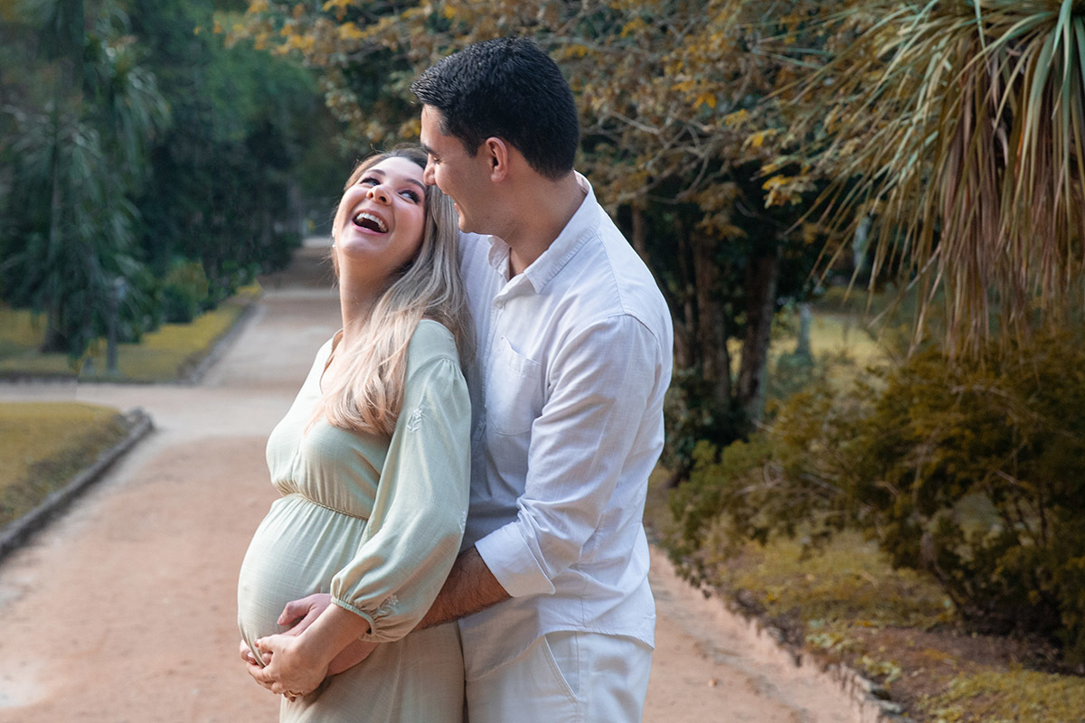 Ensaio de gestante no Jardim Botânico do Rio de Janeiro com o casal em um abraço cheio de amor.