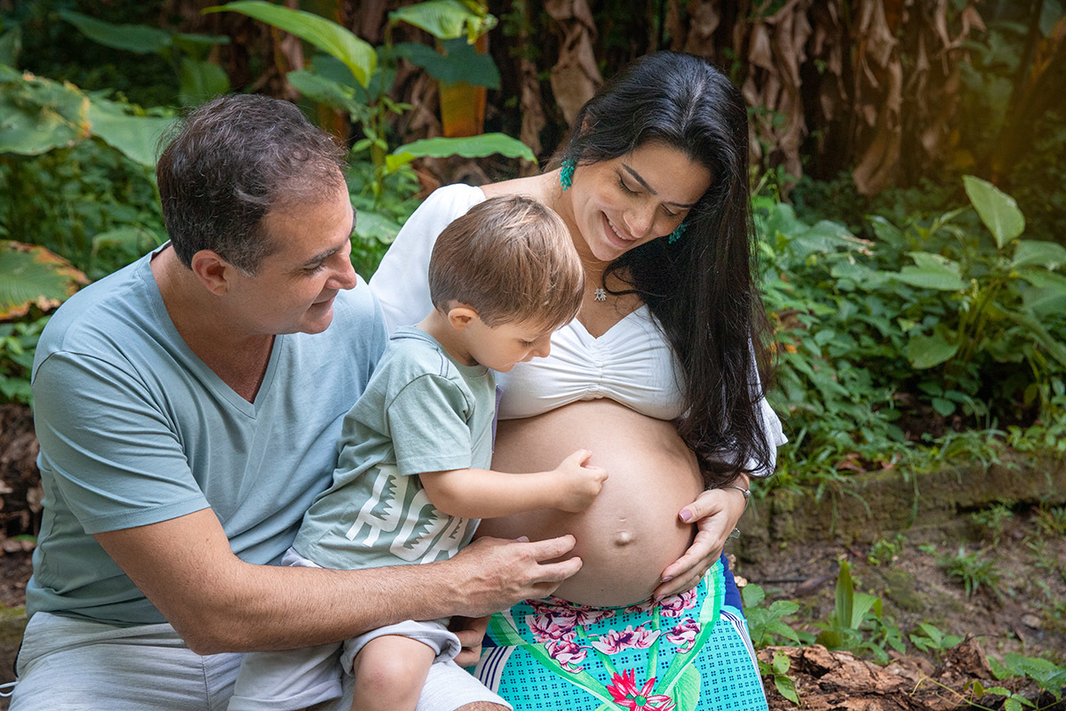 Família em ensaio gestante no Parque Lage, com pais e filhos acariciando a barriga da mamãe.
