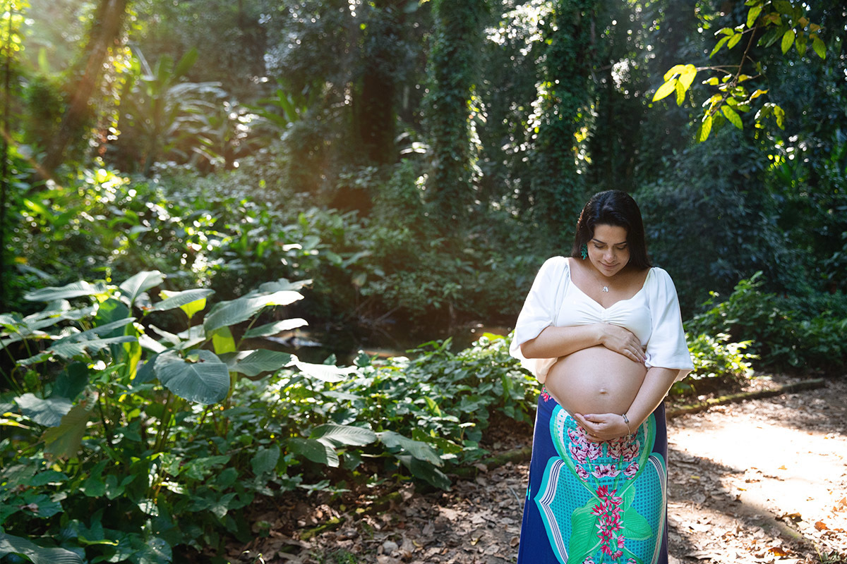 Ensaio fotográfico de gestante no Parque Lage, barriga em destaque entre as árvores.