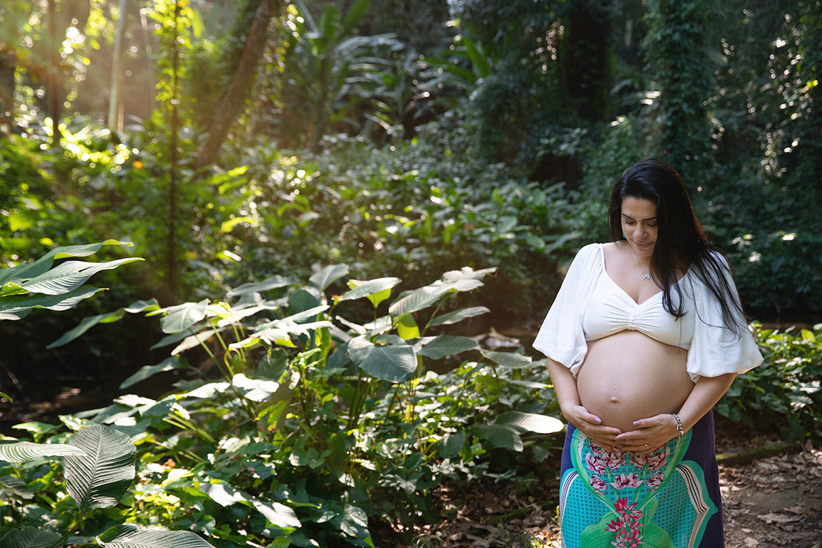 Ensaio fotográfico de gestante no Parque Lage, barriga em destaque entre as árvores.