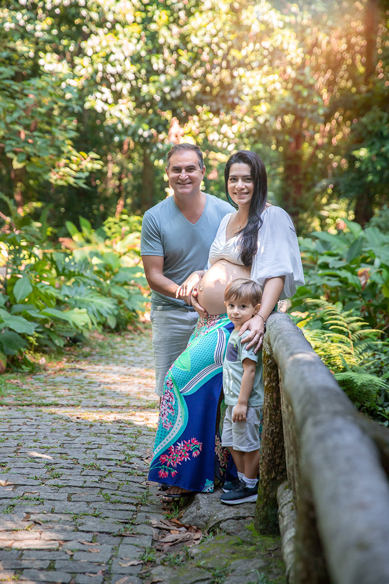 Foto de gestante e família no Parque Lage, ensaio com luz natural em meio à vegetação.