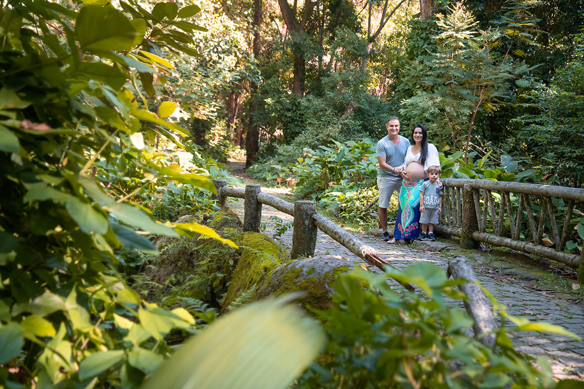 Foto de gestante e família entre árvores no Parque Lage RJ, ensaio delicado ao ar livre.