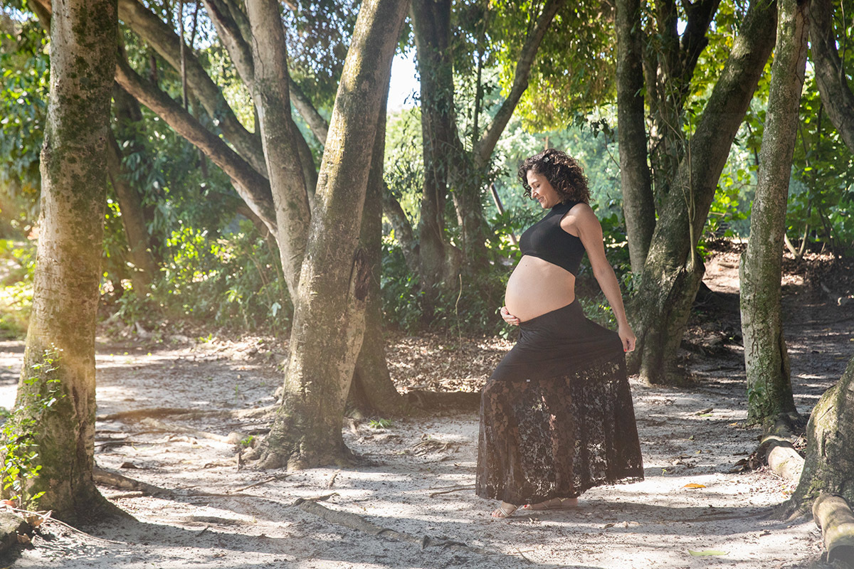 Foto de gestante em meio a troncos e sombra natural no Bosque da Barra