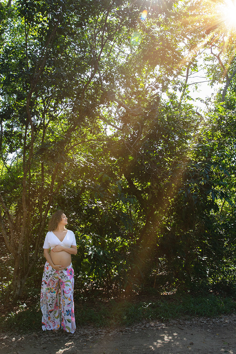 gestante com fundo de árvores e raio de sol no ensaio no Bosque da Barra no rj