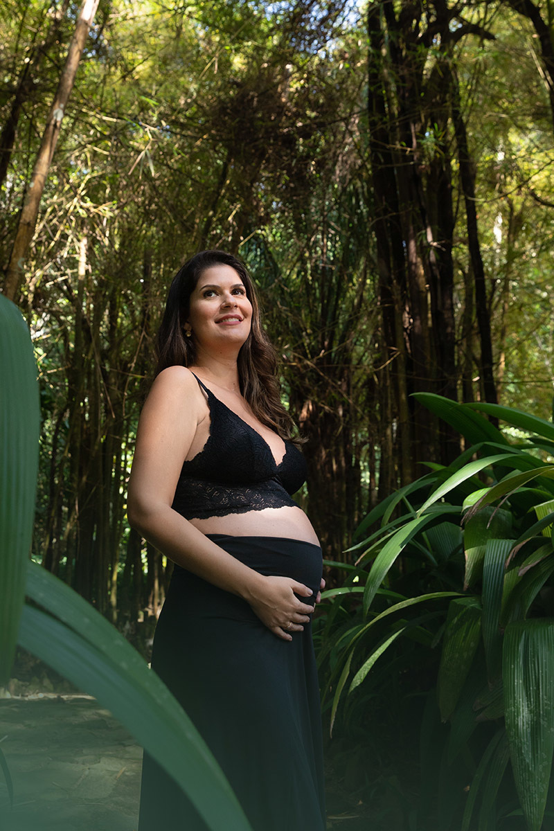 Gestante em ensaio no Jardim Botânico RJ, usando cropped de renda preta.