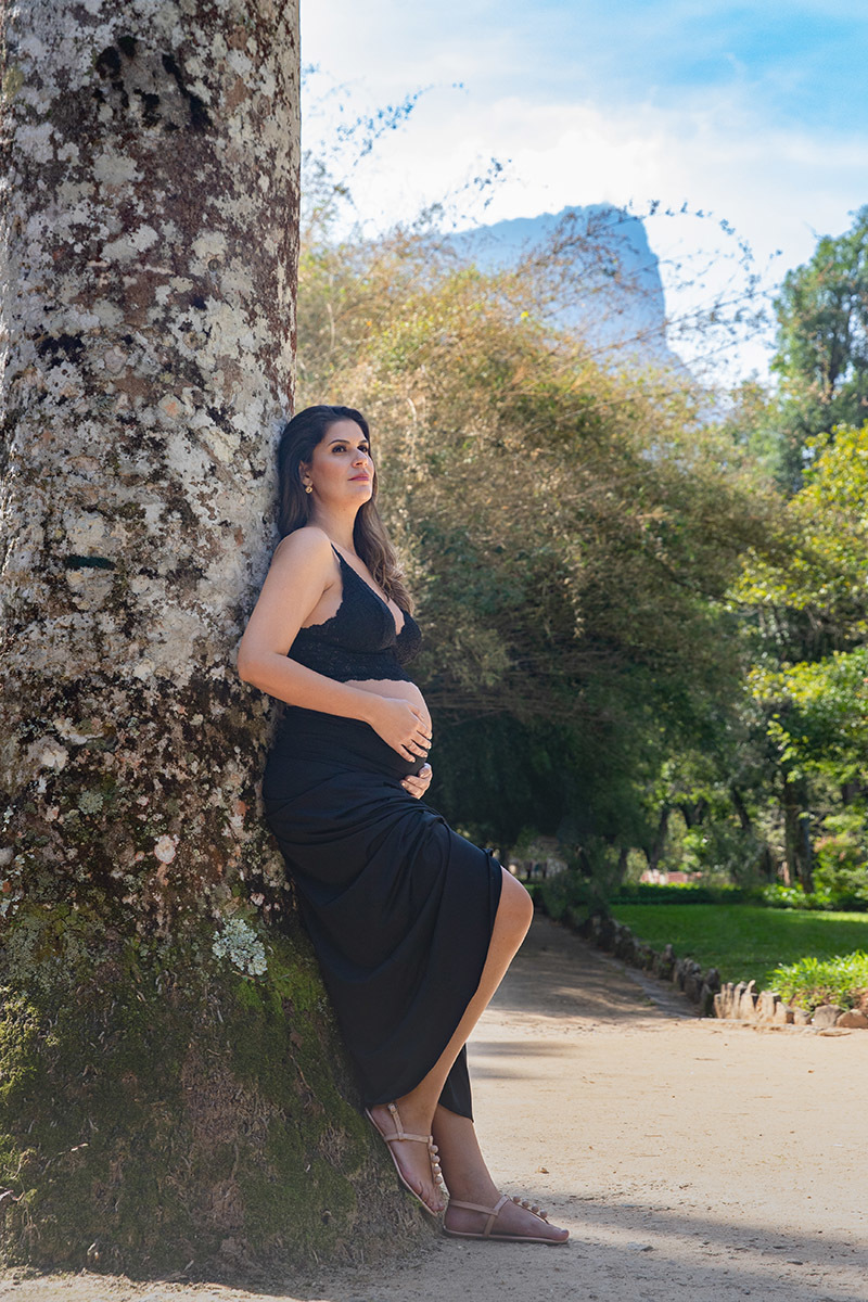 Gestante de preto encostada na árvore em ensaio no jardim botanico no Rio de Janeiro