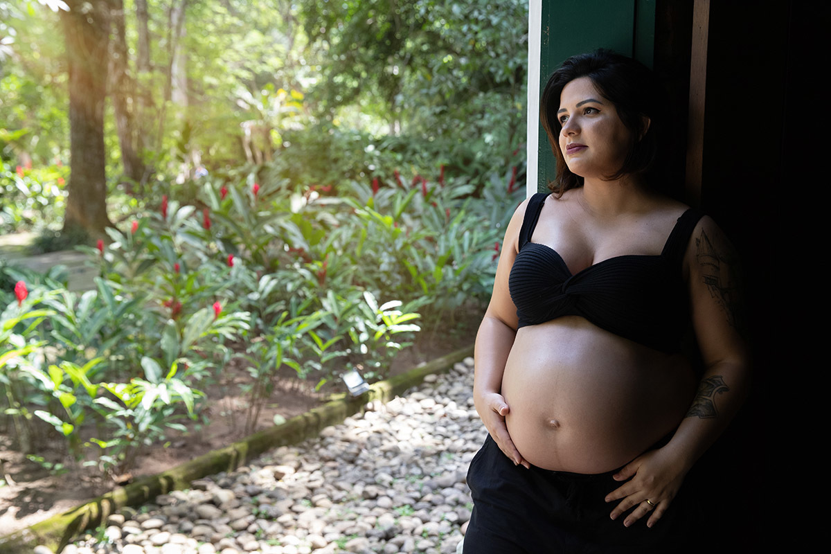 Foto de gestante no Jardim Botânico RJ em meio à natureza tropical.