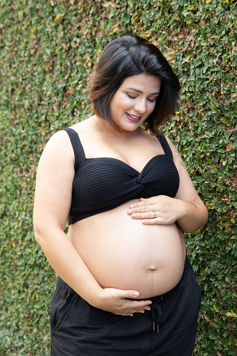 Detalhe da gestante acariciando a barriga em ensaio no Jardim Botânico.