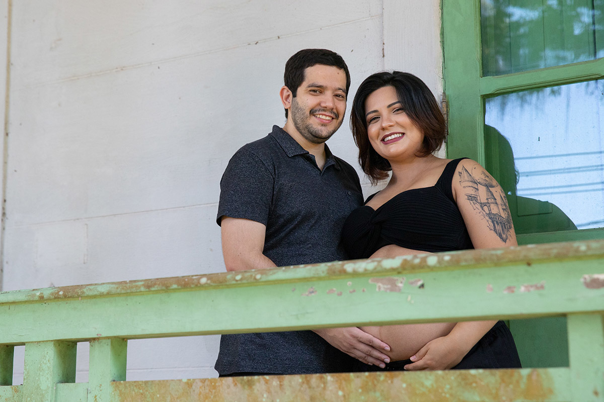 Casal sorrindo em ensaio de gestante no Jardim Botânico do Rio de Janeiro.