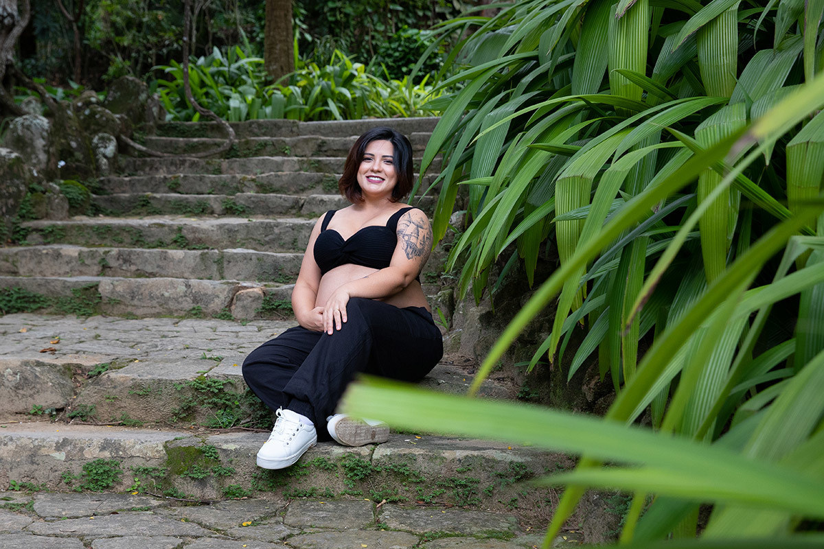 Foto de gestante em escadaria no Jardim Botânico cercada pelo verde.