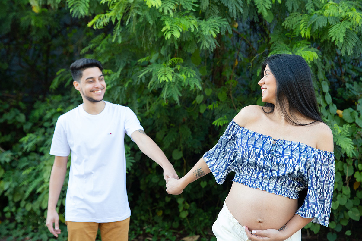 Casal de mãos dadas caminhando  durante ensaio de gestante.
