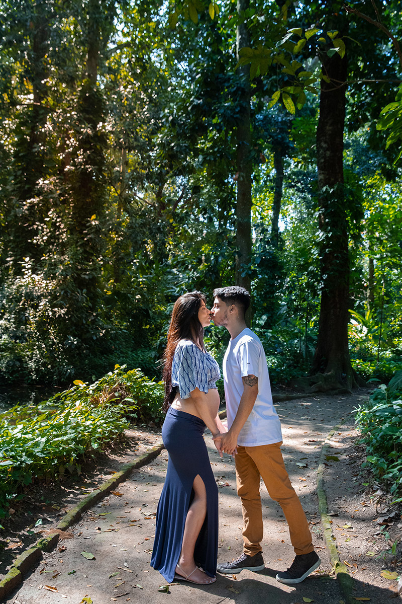 Casal sorrindo em meio à natureza no Parque Lage durante ensaio gestante.