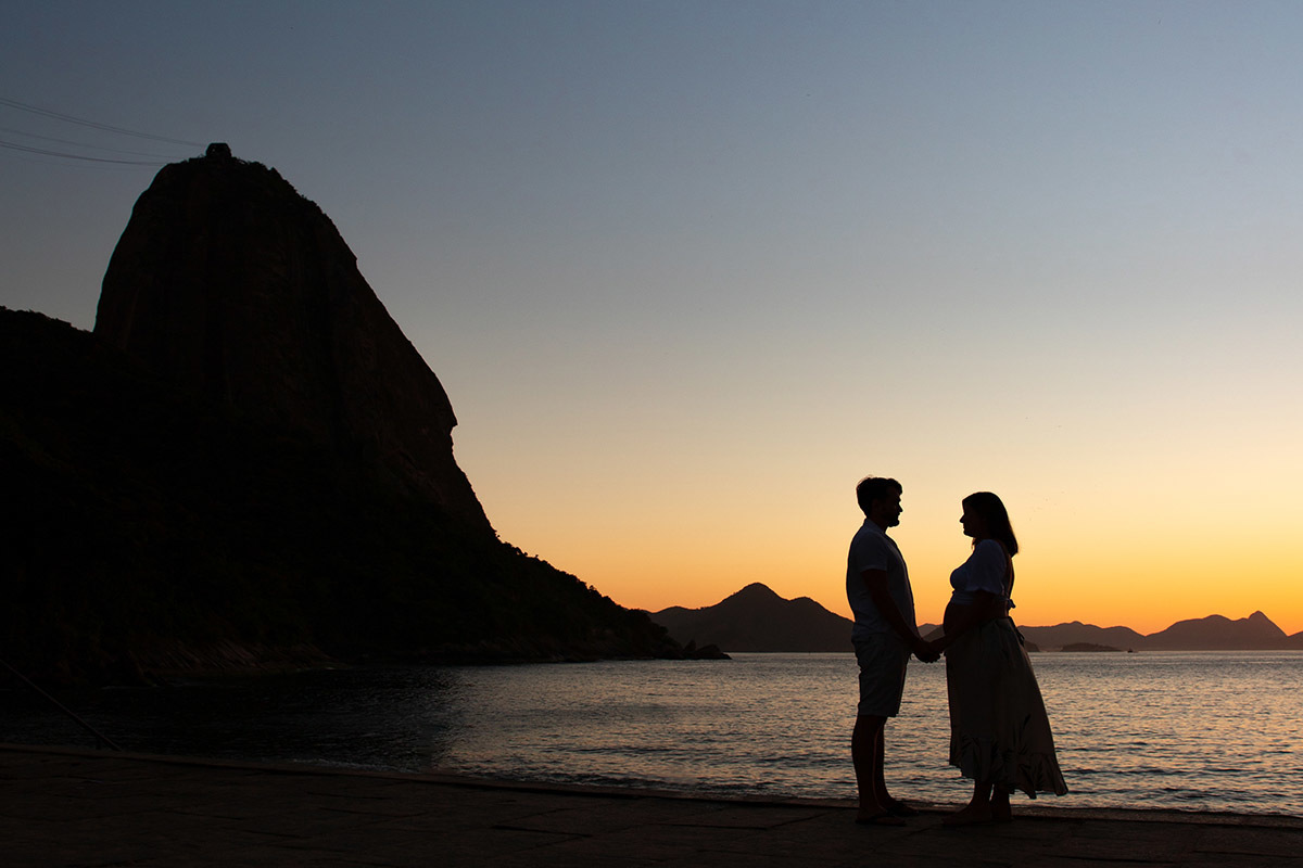 Ensaio gestante na Praia Vermelha RJ, casal em silhueta com o Pão de Açúcar ao fundo.