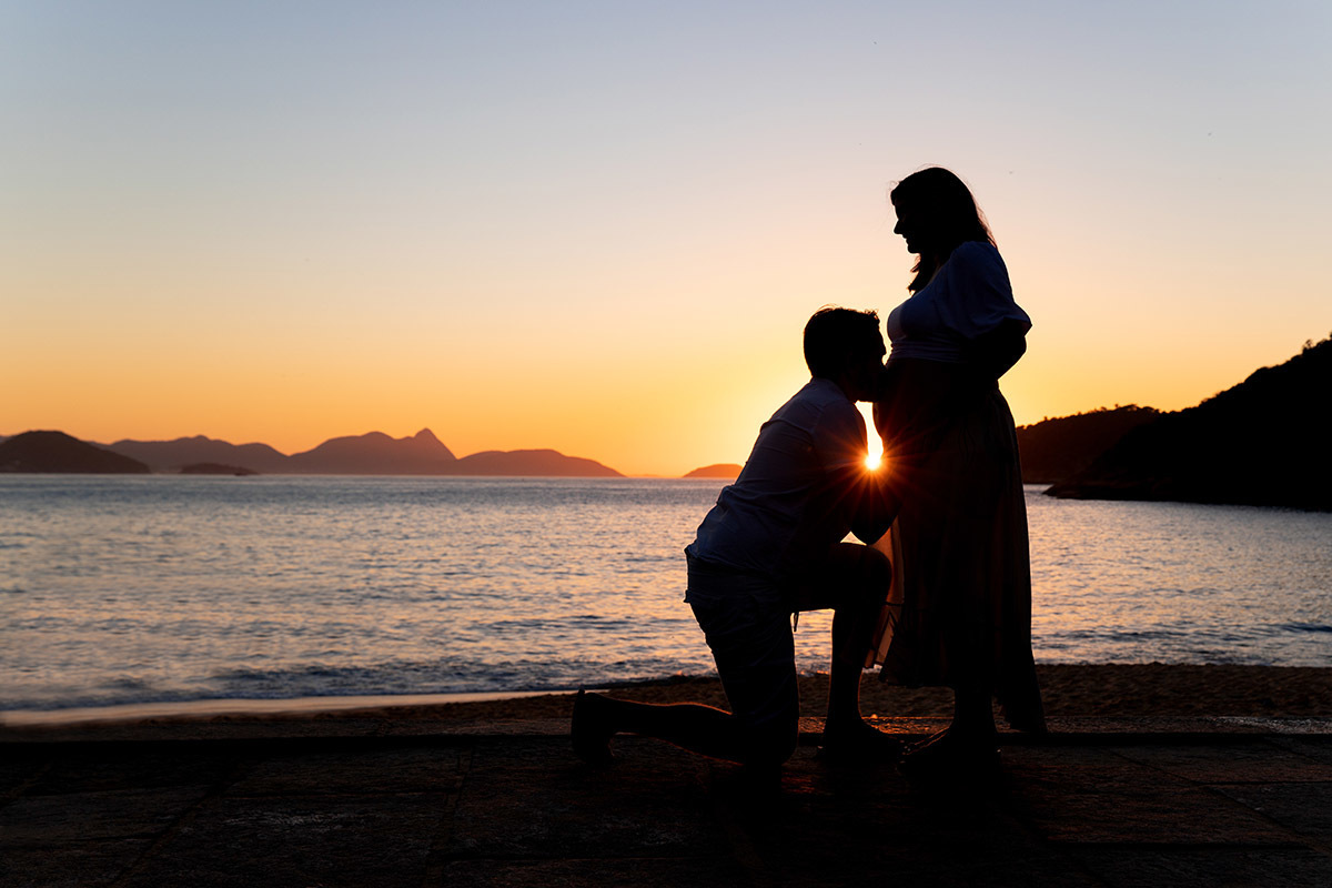 Silhueta de Casal em ensaio gestante na Praia Vermelha, com pôr do sol dourado no Rio de Janeiro.