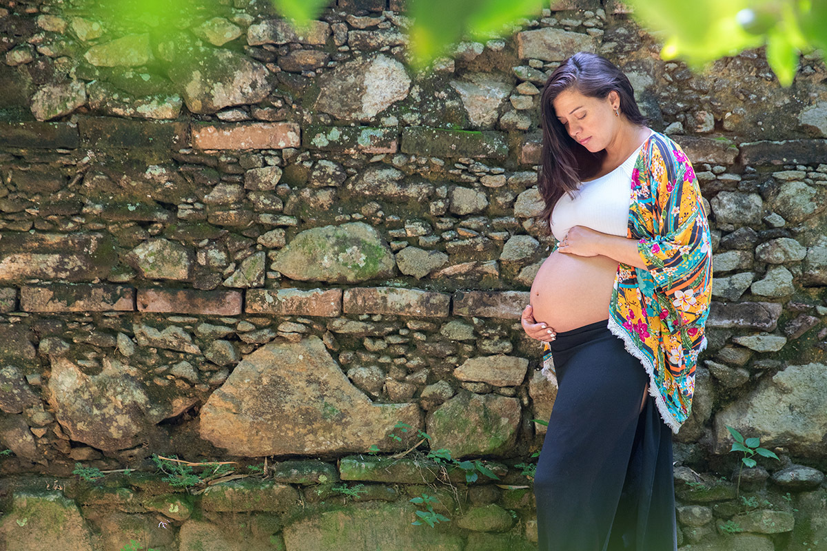 Gestante em ensaio ao ar livre no Jardim Botânico do Rio, com fundo de pedras naturais.