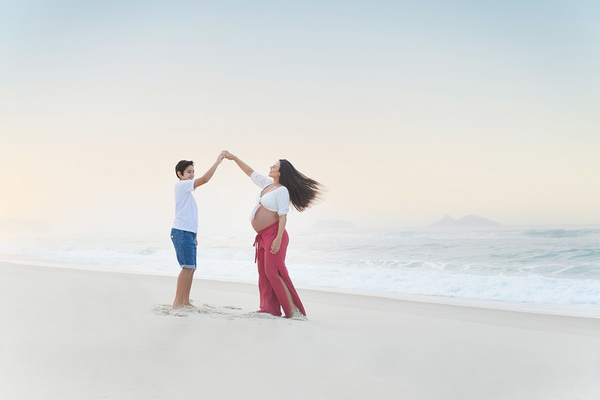 Ensaio de gestante na praia: Silvia, e Matheus dançando na areia, no Rio de Janeiro.