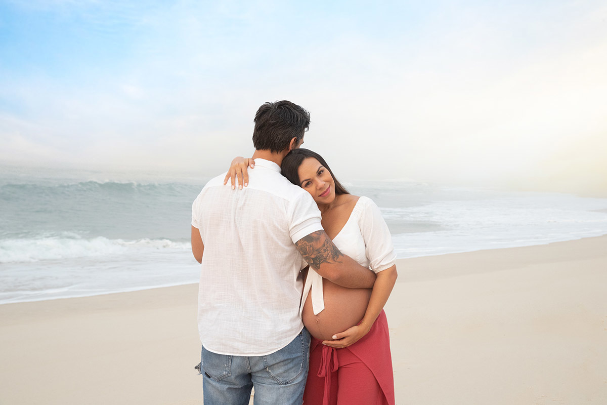 Ensaio de gestante na praia: Silvia, Sanderson abraçados, no Rio de Janeiro.