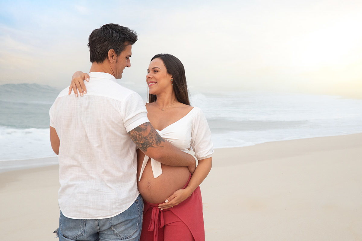 Ensaio de gestante na praia: Silvia, Sanderson se olhando, no Rio de Janeiro.