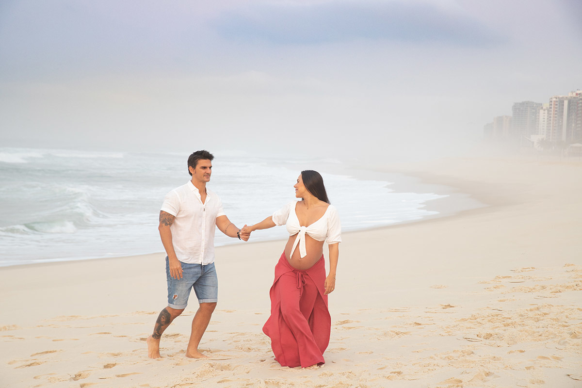 Ensaio de gestante na praia: Silvia, Sanderson andando na areia, no Rio de Janeiro.