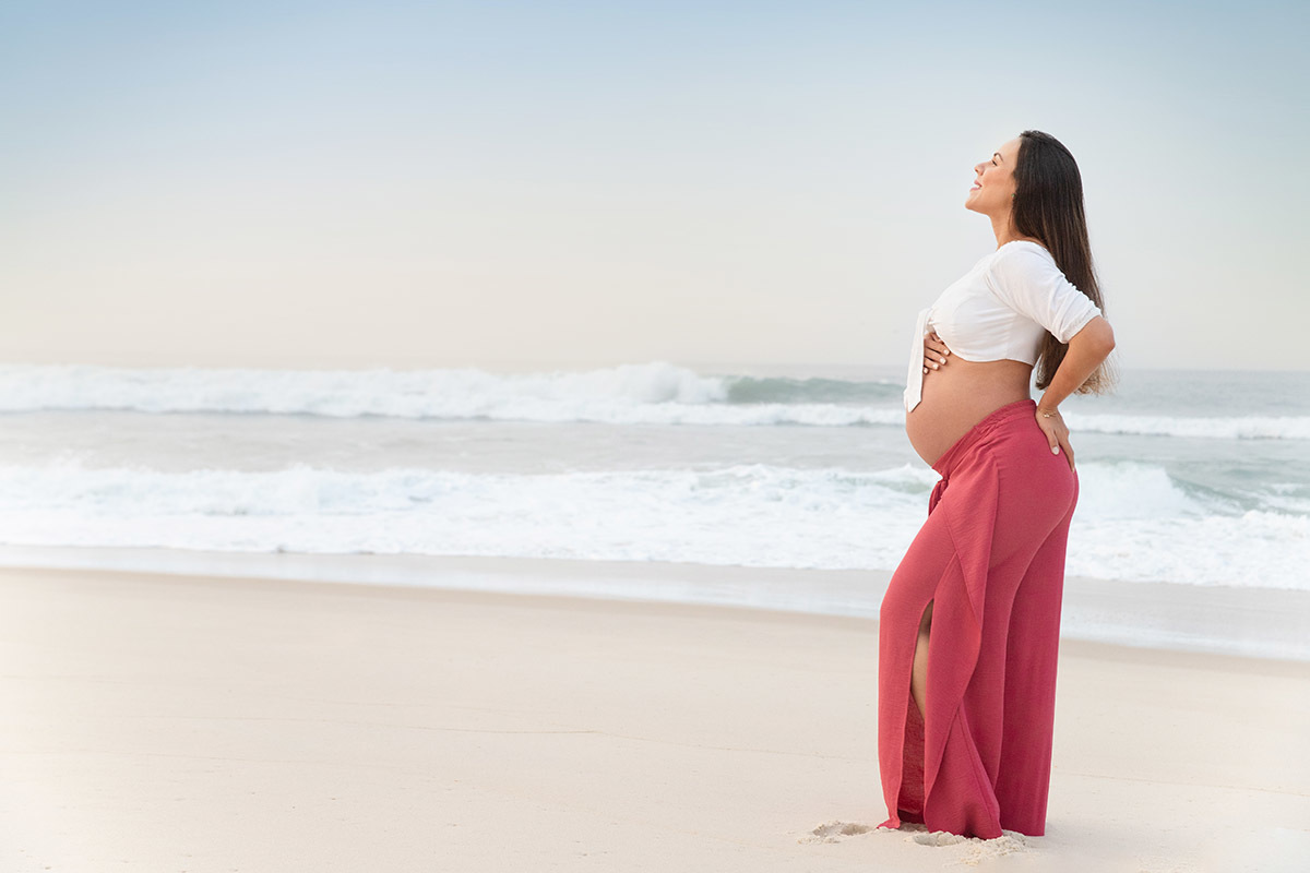 Ensaio de gestante na praia: Silvia, olhando para o céu, no Rio de Janeiro.