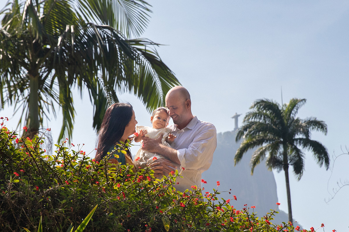 Mãe e pai com a filha no colo e Cristo Redentor ao fundo