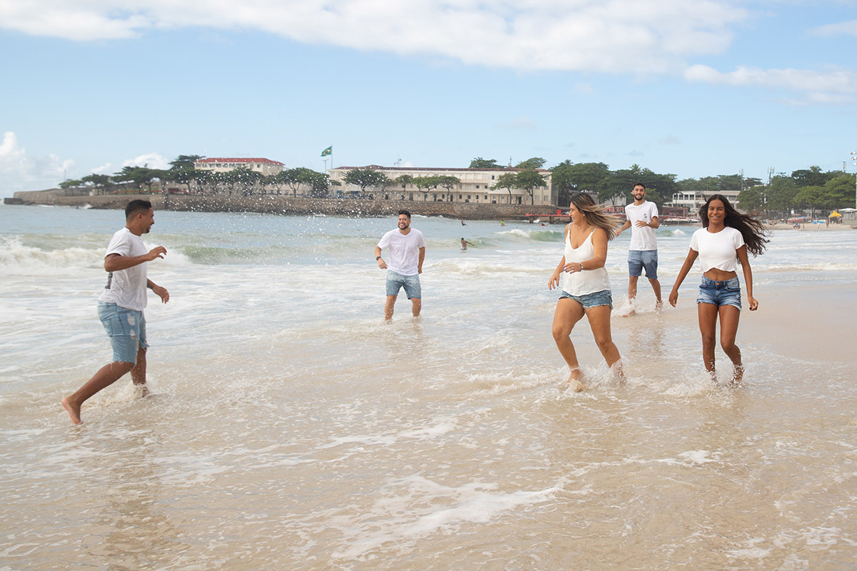Ensaio família na praia de Copacabana: Nehylza correndo na areia com a família no Rio de Janeiro.