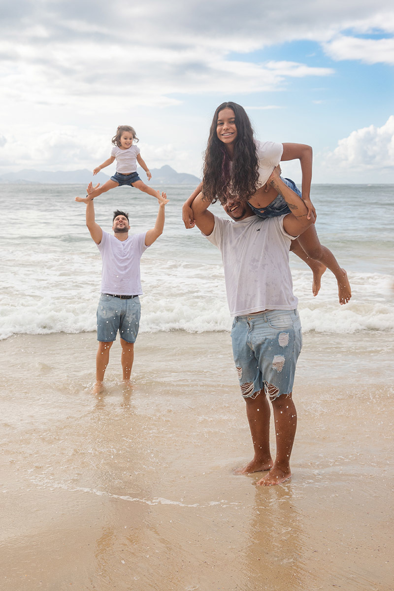 Ensaio família na praia de Copacabana:  irmãos brincando na areia no Rio de Janeiro.