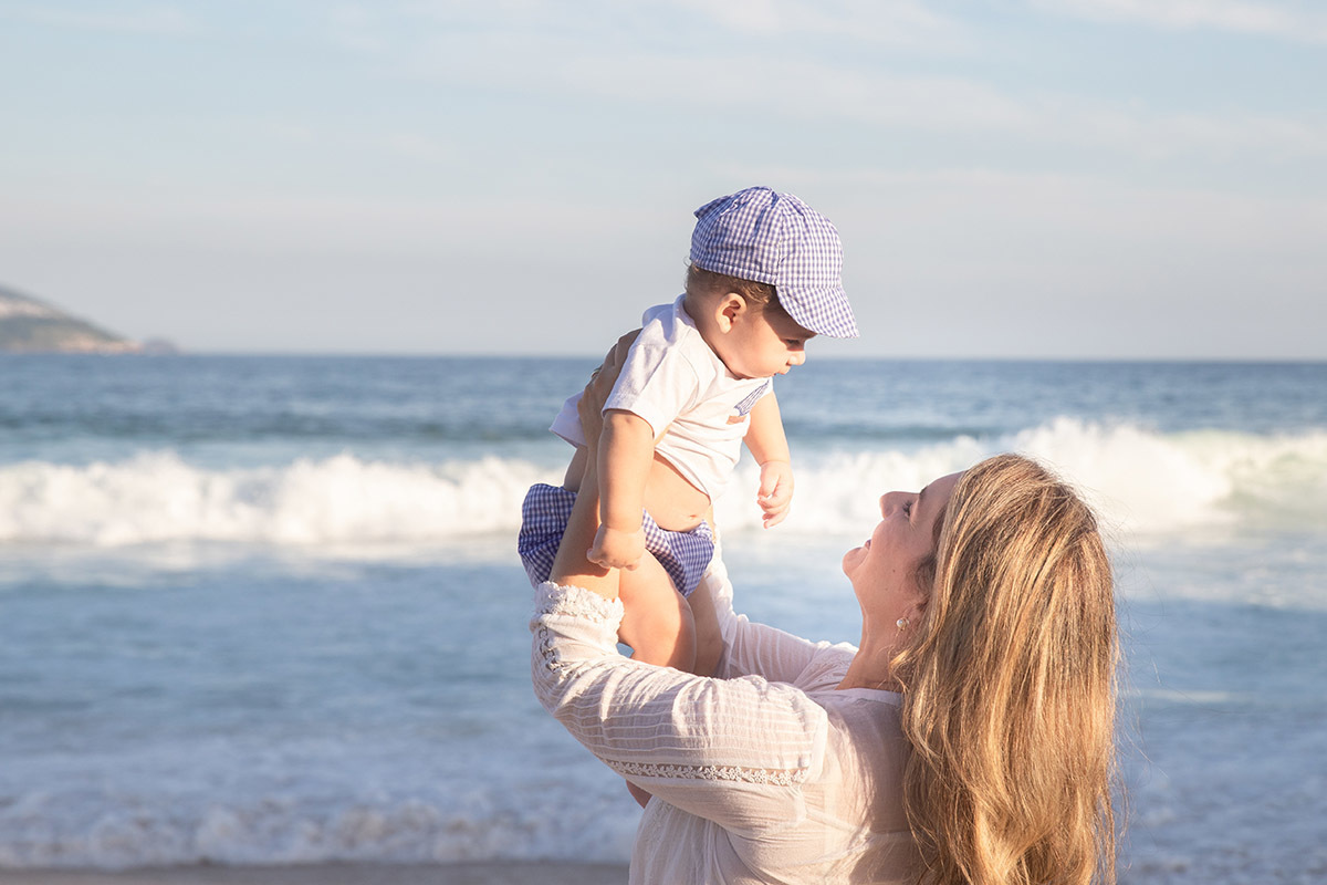 Ensaio bebê na praia: Vitor no colo da Lu no Rio de Janeiro.