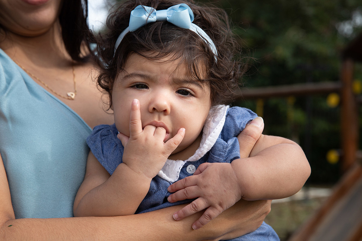 Ensaio de bebê: Ester com a mão na boca no jardim no Rio de Janeiro.