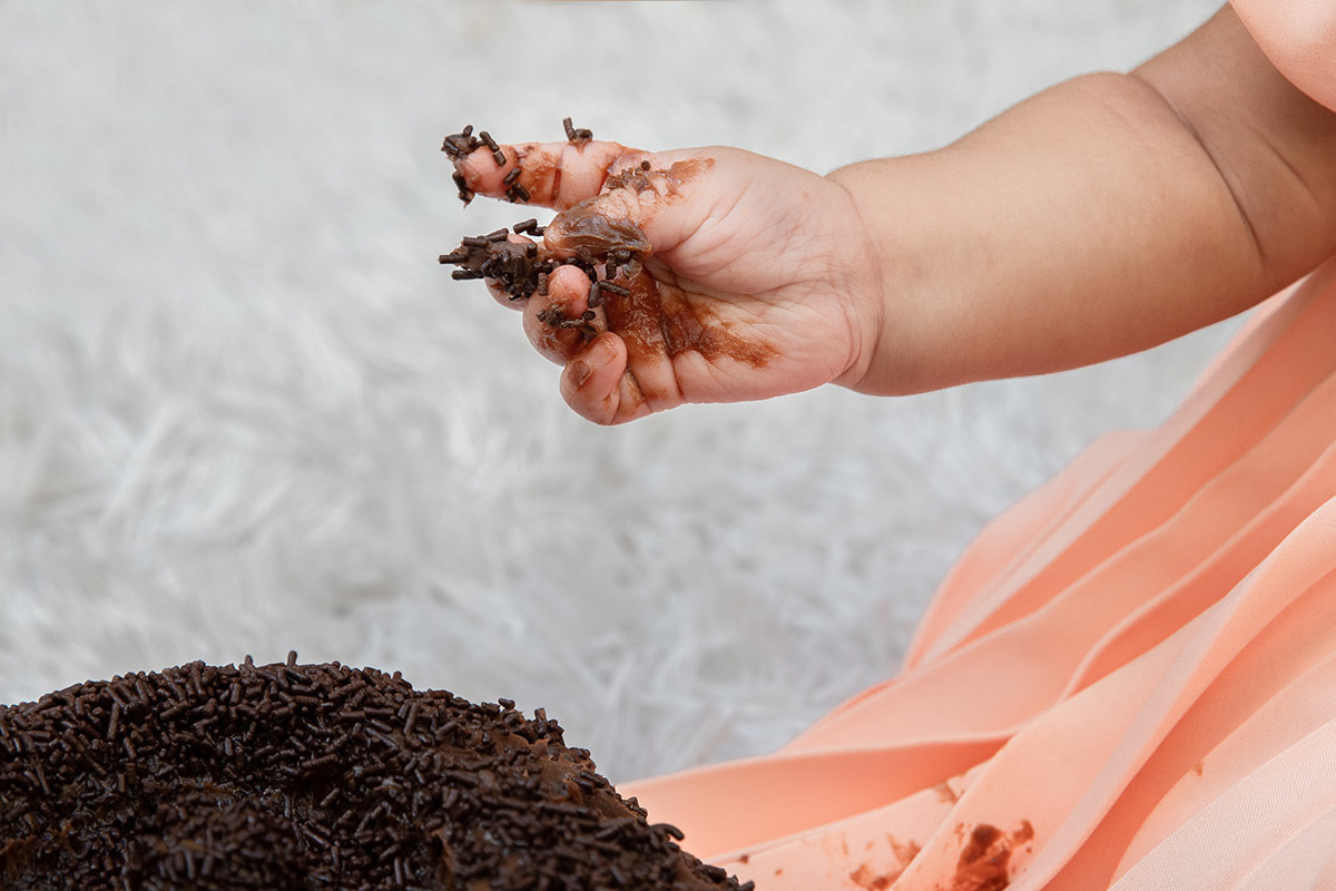 Ensaio de bebê: Ester com a mão suja de bolo no Rio de Janeiro.