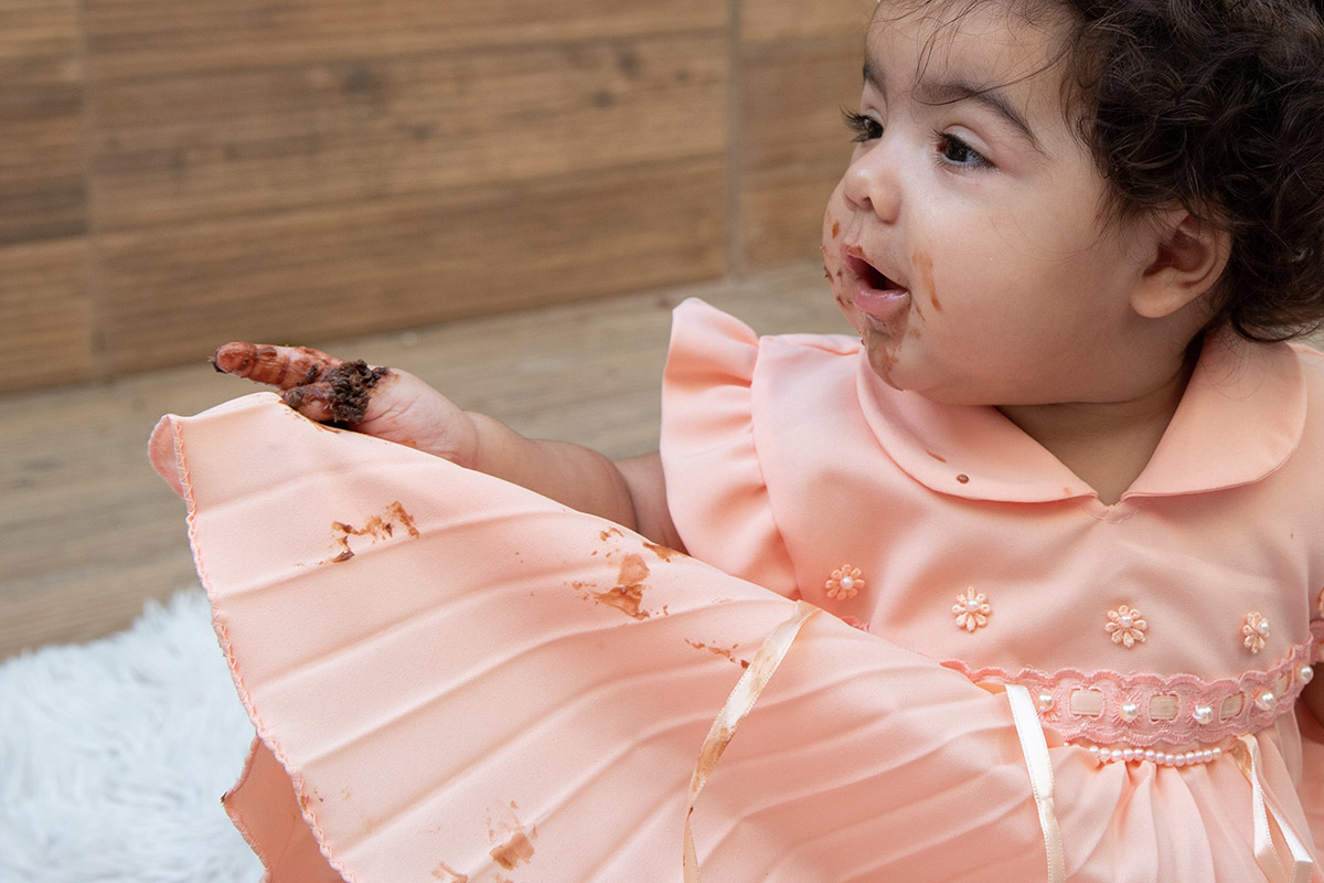 Ensaio de bebê: Ester com a mão e boca sujas de bolo no Rio de Janeiro.