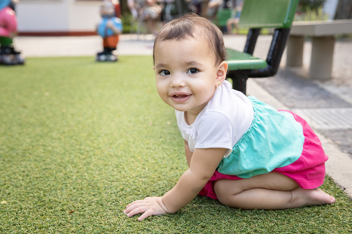 Ensaio de Família no Clube Piraquê: Laura brincando na grama, no Rio de Janeiro.