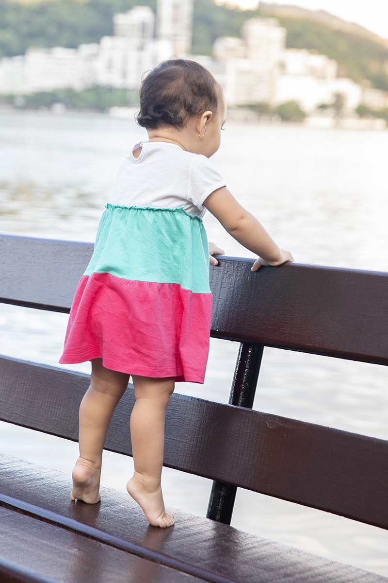Ensaio de Família no Clube Piraquê: Laura no banco olhando para a Lagoa, no Rio de Janeiro.