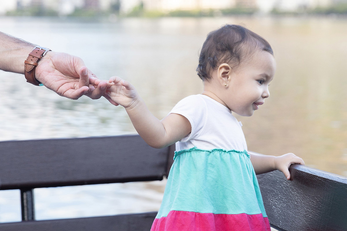 Ensaio de Família no Clube Piraquê: Laura no banco olhando para a Lagoa, no Rio de Janeiro.